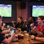 Exciting sports betting scene with friends enjoying zbet app in vibrant lounge.