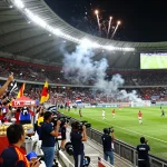Football match atmosphere with fans cheering and players in action during a thrilling game involving ฟุตบอล.