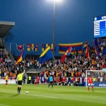 Soccer fans celebrating with "ผลบอล" visible on the scoreboard during an exciting match.